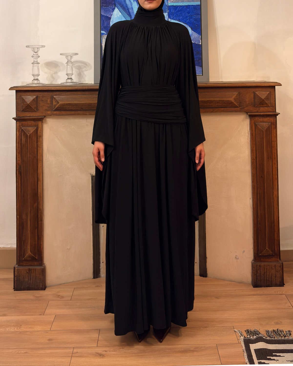 Robe longue noire à manches drapées de la marque LUMYRA, élégante et fluide, portée avec un décolleté en V.